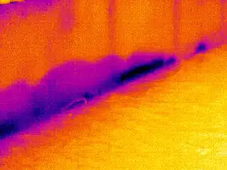 Infrared imagery shows temperature differences of wall and floor, as illustrated by color variation.