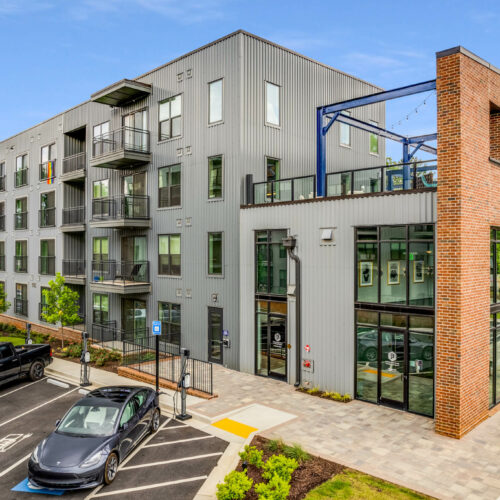 Exterior view of Broadstone Pullman, a modern mixed-use development with residential units and commercial space, featuring contemporary design elements such as large windows, balconies, and a combination of brick and metal facades.