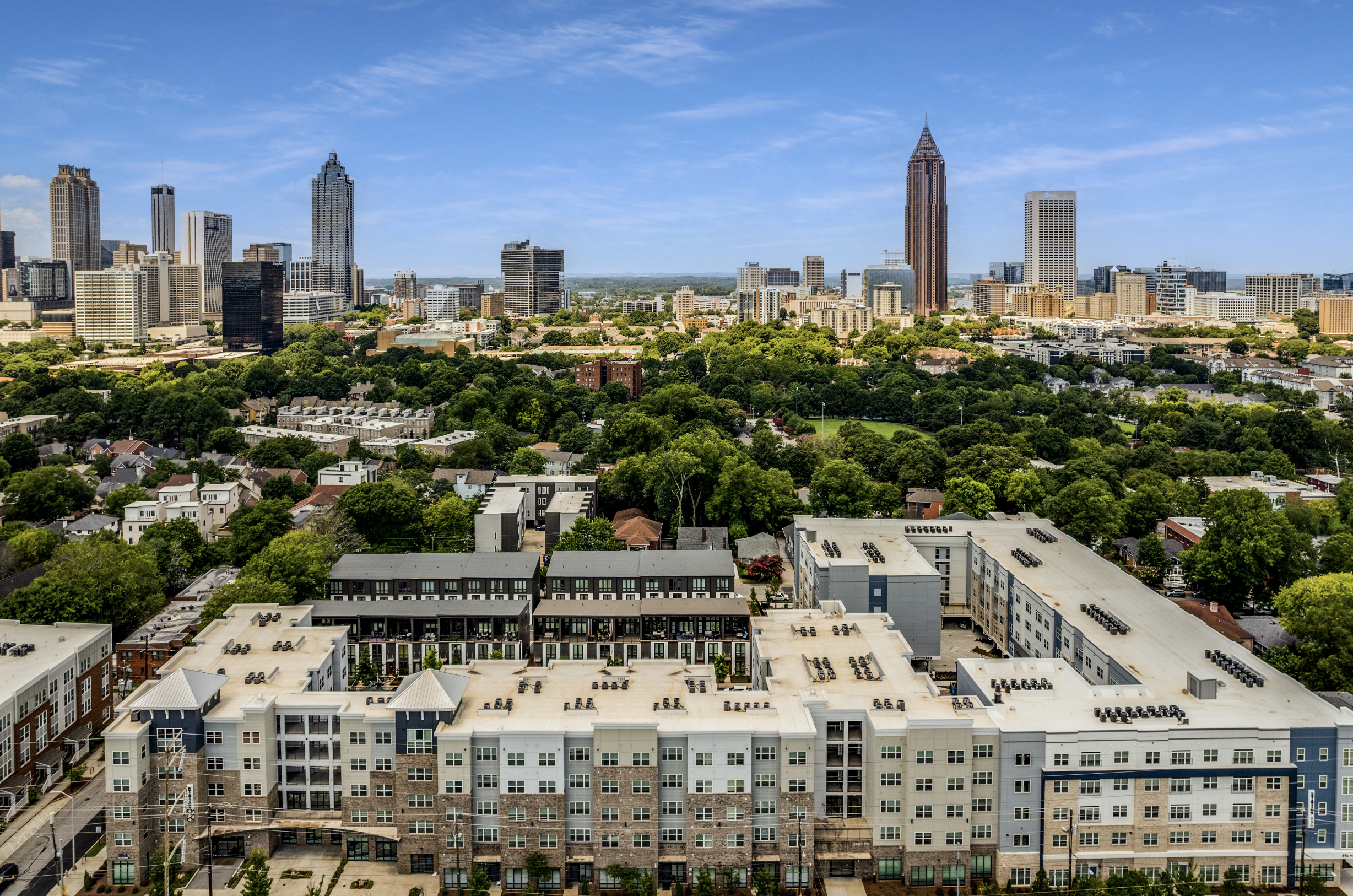 Aerial view of Station 496 in Atlanta, showcasing the expansive complex with the city's skyline in the background. The buildings feature modern design elements and are surrounded by lush greenery.